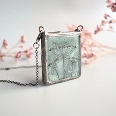 "Keep the nature close to your heart wherever you are. This is a hand painted Queen Anne's Lace flower pendant in a unique green-gray color.  Waste window glass gets a new life as pieces of art to wear. Perfect sustainable gift for someone you care about, that care about the environment. The two lobster clasps make it a thoughtful gift for someone with weakness in hands and arms, it's easy to put on from the front, in addition to just being cool and different. Two functionalities in one item! Wh Nature-inspired Hand Painted Necklace For Gift, Hand Painted Nature-inspired Necklace For Gift, Green Handmade Necklace For Keepsake, Green Hand Painted Necklace For Gift, Green Necklace With Natural Inclusions For Gift, Green Botanical Necklace Perfect For Gifting, Green Botanical Necklace For Gift, Green Botanical Necklace For Gifts, Green Botanical Style Necklace For Gift