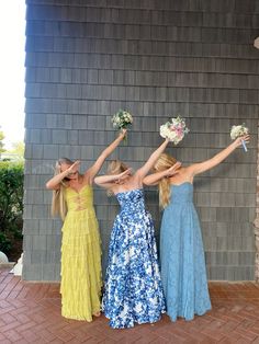 three beautiful young women standing next to each other holding bouquets in their hands and posing for the camera