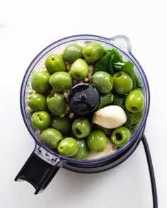 a blender filled with green peppers and other vegetables on top of a white table