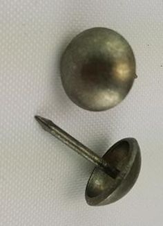 two metal knobs and a screw on a white surface with some holes in the middle