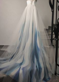 a dress is on display in front of stairs and railings, with an artisticly painted skirt