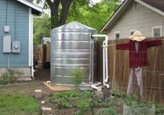 a man standing next to a large metal tank in a yard with a fence around it