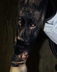 a man's arm with a wolf tattoo on it and trees in the background