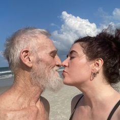 an older man and woman kissing on the beach