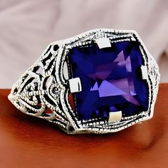 Elevate your jewelry collection with this stunning Vintage 3.00 Carat Princess Cut Vivid Purple Lab-Created Amethyst Solitaire Filigree Ring, a true masterpiece crafted for those who appreciate timeless elegance and unique design. Made from 925 Solid Sterling Silver, this exquisite ring is not only beautiful but also durable, ensuring it remains a cherished piece for years to come. The ring is stamped "925," guaranteeing its authenticity and quality. The vivid purple hue of the lab-created amethyst captures the eye, making it a statement piece perfect for any occasion, whether it's a formal event or a casual outing with friends. This ring stands out with its intricate filigree detailing, showcasing a blend of traditional craftsmanship and modern design aesthetics. The princess cut of the a Silver Filigree Ring With Birthstone For Anniversary, Antique Silver Amethyst Ring For Anniversary, Silver Birthstone Rings Collectible, Silver Birthstone Rings For Collectors, Silver Hallmarked Amethyst Ring For Anniversary, Classic Silver Amethyst Ring For Anniversary, Vintage Silver Amethyst Ring For Anniversary, Classic Jewelry With Accent Stones For Collectors, Classic Collectible Jewelry With Accent Stones