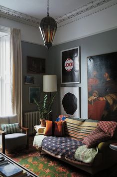 a living room filled with furniture and paintings on the wall above it's windows