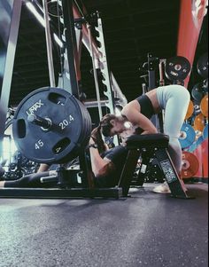 a woman squatting down in front of a barbell