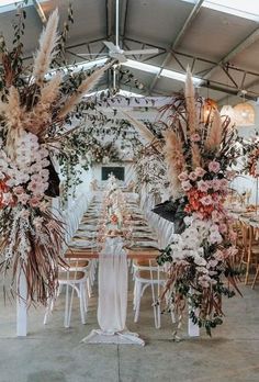 an arrangement of flowers and greenery decorates the tables