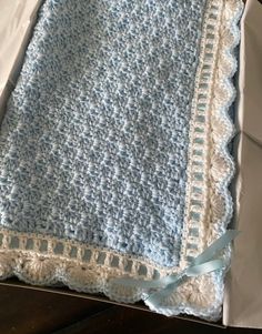 a blue and white crocheted blanket sitting on top of a table