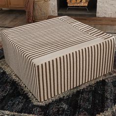 a striped ottoman sitting on top of a rug next to a fire place in a living room