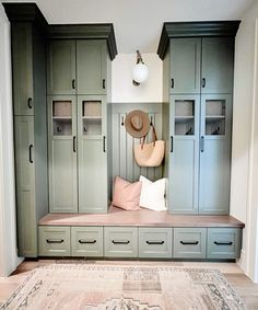 a room with some green cabinets and a hat on the bench in front of it