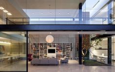 an open living room with glass walls and floor to ceiling bookshelves is shown