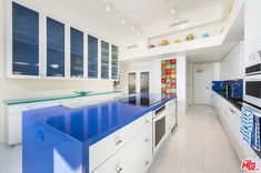 a large kitchen with blue counter tops and white cabinets, along with lots of windows