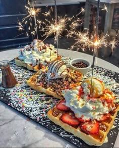 two waffles topped with ice cream, strawberries and whip cream surrounded by sprinkles