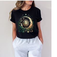 PLEASE ORDER BY DECEMBER 13TH TO ENSURE DELIVERY BY CHRISTMAS.  THANK YOU SO MUCH! Retro Celestial, Botanical and Wildflower Shirt .This Shirt is the best and one of a kind. Boho Botanical Cosmic Nature Lover Moon shirt is sure to make you stand out in any crowd and can be worn on any occasion.  Order now,  you don't want to miss out on this beautiful Celestial Shirt. Thank you for visiting our small shop. This classic unisex jersey short sleeve tee fits like a well-loved favorite. Soft cotton and quality print make users fall in love with it over and over again. These t-shirts have-ribbed knit collars to bolster shaping. The shoulders have taping for better fit over time. Dual side seams hold the garment's shape for longer.  .: 100% Airlume combed and ringspun cotton (fiber content may va Trendy Spring Tops With Moon Print, Casual Moon Print Tops For Spring, Casual Spring Tops With Moon Print, Summer Moon Print Crew Neck Top, Summer Short Sleeve Top With Moon Print, Bohemian Short Sleeve T-shirt With Sun And Moon Design, Bohemian Cotton T-shirt With Sun And Moon Design, Summer Moon Print Graphic Tee, Summer Graphic Tee With Moon Print