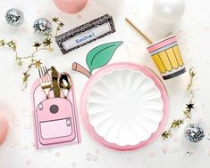 a table topped with pink plates and decorations