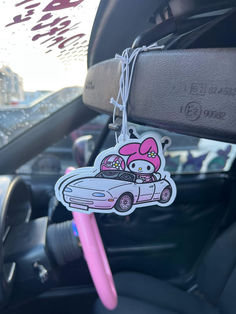 a hello kitty car keychain hanging from the side of a car with a pink pen in it