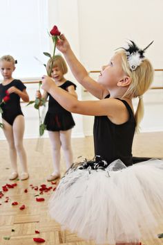 three young ballerinas in tutu and leotards with rose petals on the floor