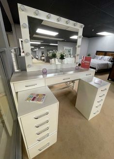 a white desk with drawers and a mirror on it in a room filled with furniture