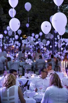 many people are sitting at tables with white balloons in the shape of heart - shaped shapes