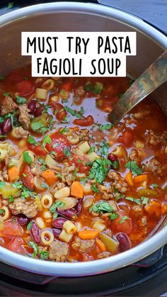 a large pot filled with pasta and meat soup next to a wooden spoon on top of a stove