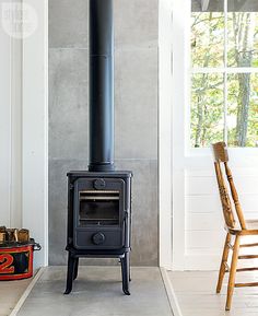 a black stove sitting in the corner of a room next to a chair and window