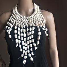 Elevate your style with this handmade cowrie shell bib necklace. Beautifully polished ivory, ring top cowrie shells. 2 styles: Classic 5 Row OR Elegant Drops Ivory Ring, Off The Shoulder Tee, Cowry Shell, Wide Neck Sweatshirt, Cowrie Shells, Printed Halter Dress, Dropped Shoulder Sweatshirt, Bib Necklaces, Just Because Gifts