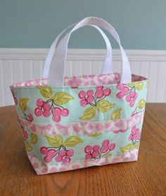 a pink and green bag sitting on top of a wooden table next to a wall