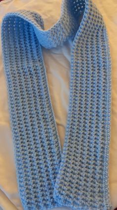 a blue knitted scarf laying on top of a bed