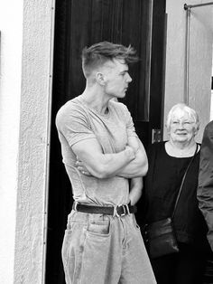 black and white photograph of three people standing in front of a door with their arms crossed