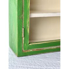 an old green painted wooden cabinet with two shelves and one door open on the side