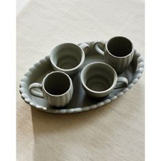 four coffee cups are sitting on a tray with saucers in the shape of a boat