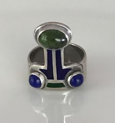 "There is a hint of arts and crafts, as well as, modernist in this unusual ring which you can wear with the Peridot facing up or down! The beautiful green stone, as well as the smaller vibrant blue Lapis are all cabochon and bezel set. The enamel is in wonderful condition. Aside from some slight wear, the ring is in overall fabulous shape. The band is almost 1/4\" wide, it is marked Sterling and has the initials CHM scratched on the silver behind the Peridot. Please see all photos for details, a Lapis And Peridot, Unusual Rings, Geometric Ring, Gold Snake, Peridot Ring, Charm Rings, Silver Enamel, Green Stone, Amethyst Ring