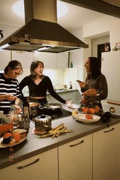 three women in a kitchen preparing food on a counter top with pots and pans