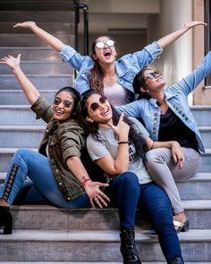 four women sitting on the steps with their arms in the air