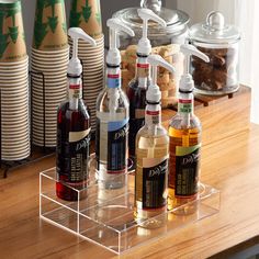 several bottles of alcohol on a counter with plates and cups in the backround