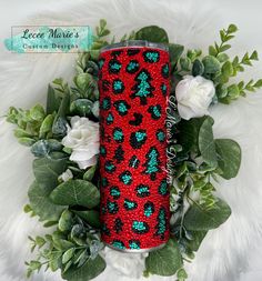 a red and black leopard print can cooler next to white flowers