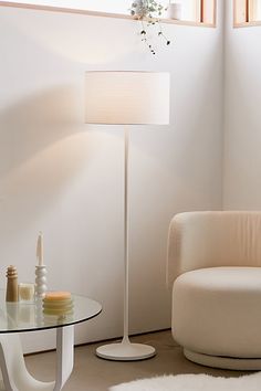 a living room with a chair, table and lamp in it's centerpiece