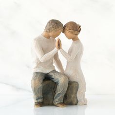 two figurines sitting next to each other holding hands