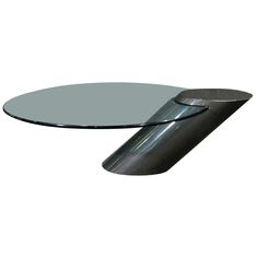 an oval glass table with metal legs and a circular base on the top, against a white background