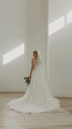 a woman in a wedding dress is standing on the floor with her back to the camera