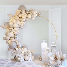 the balloon arch is decorated with white and silver balloons, gold accents, and flowers