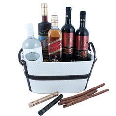 an assortment of liquors and cinnamon sticks in a white basket with black trimming