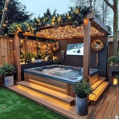 an outdoor hot tub surrounded by lights and potted plants in the middle of a wooden deck