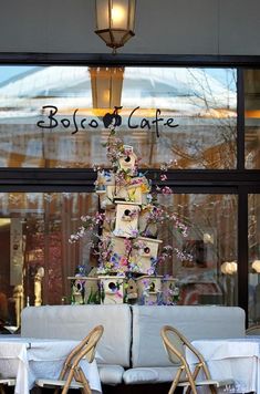 two chairs and a table in front of a store window with a cake on it