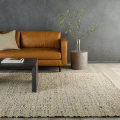 a brown leather couch sitting on top of a wooden floor next to a coffee table