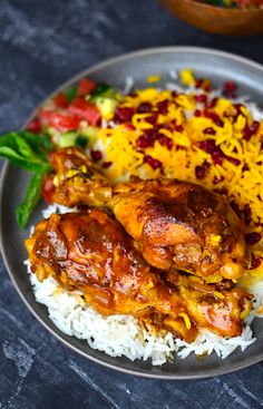 a plate with rice, chicken and vegetables on it next to a bowl of sauce