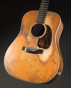 an old guitar is sitting on a black background