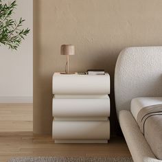 a white couch sitting next to a table with a lamp on it's side