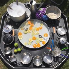 an outdoor table with pots and pans on it, lemon slices are arranged in the middle